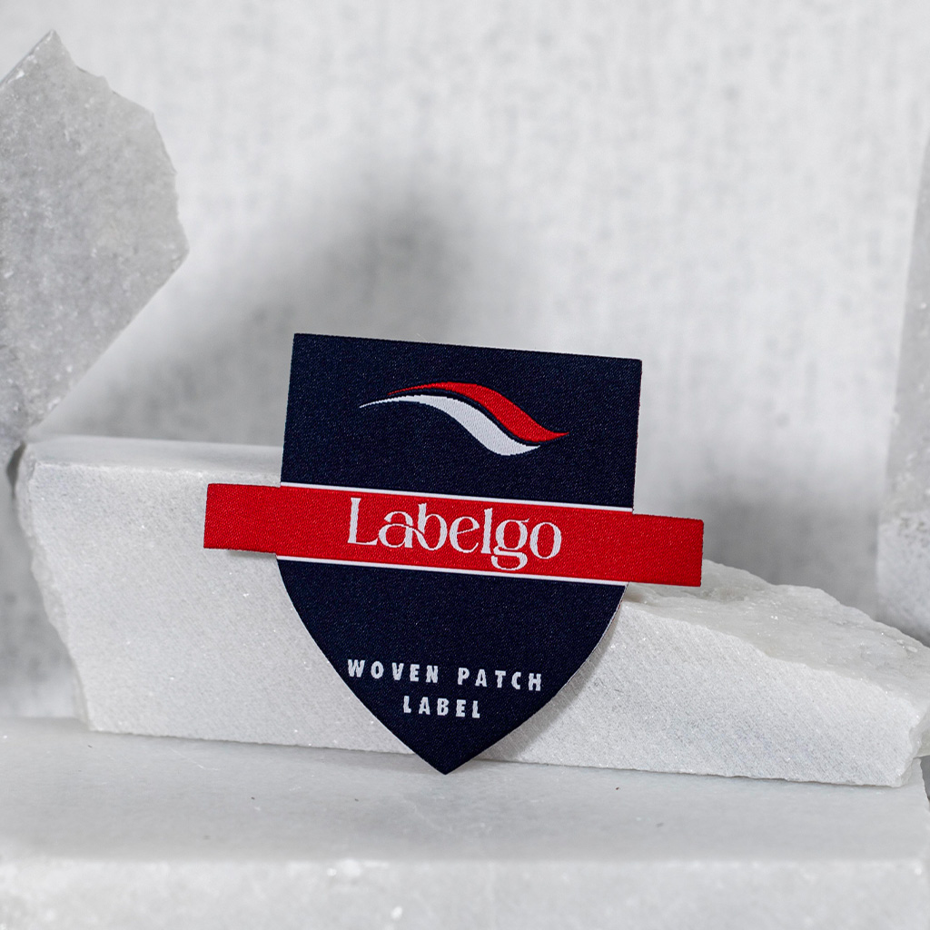 Distintivo tessuto LabelGo con logo ricamato per brand di abbigliamento.